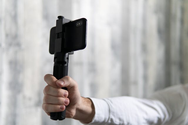 Person holding a phone with a tripod